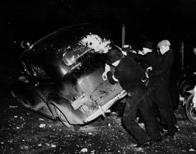 A group of strike sympathizers is shown tipping over an automobile loaded with sheriff’s deputies during the riot at the strike-closed Fisher Body#2
