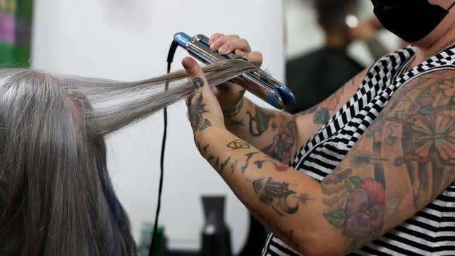 A salon worker using a curling iron.