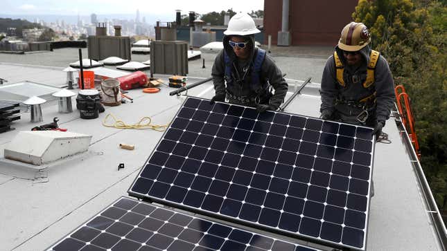 Workers install solar panels on the roof of a home on May 9, 2018 in San Francisco, California.