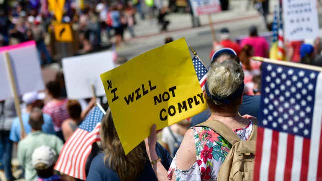 A demonstrator holds a placard stating “I WILL NOT COMPLY” during a rally outside the Pennsylvania Capitol Building regarding the continued closure of businesses due to the coronavirus pandemic on May 15, 2020 in Harrisburg, Pennsylvania. Pennsylvania Governor Tom Wolf has introduced a color tiered strategy to reopen the state with most areas not easing restrictions until June 4. 