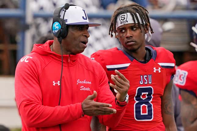 Jackson State football coach Deion Sanders, left, confers with quarterback Quincy Casey (8) during the second half of an NCAA college football game against Edward Waters in Jackson, Miss., Sunday, Feb. 21, 2021. 