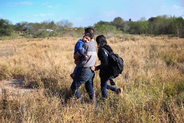 A father carries his sleeping son, 3, after their family illegally crossed the U.S.-Mexico border on December 7, 2015 near Rio Grande City, Texas