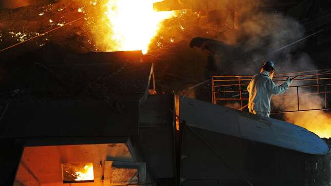 A worker pries up molten cast iron from a blast furnace at a plant of Dongbei Special Steel Group on July 17, 2018 in Dalian, Liaoning Province of China.