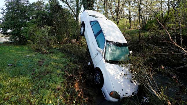 A car that was carried by floodwaters leans against a tree in a creek in Nashville.