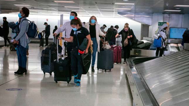 Travelers retrieve their luggage at Newark International Airport on November 21, 2020 in Newark, New Jersey. - Current US numbers — more than a quarter of a million deaths have been reported — have alarmed authorities enough to advise that people stay home for the November 26 Thanksgiving holiday, when Americans usually travel to be with their families.