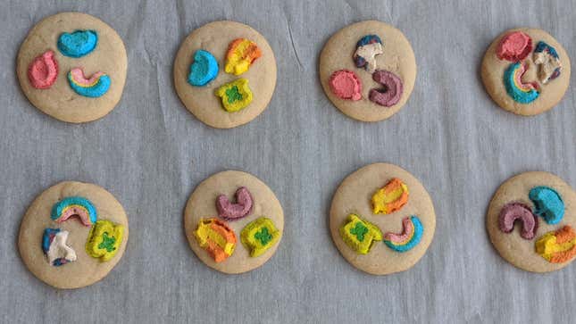 Eight cookies dotted with Lucky Charms marshmallows on white parchment