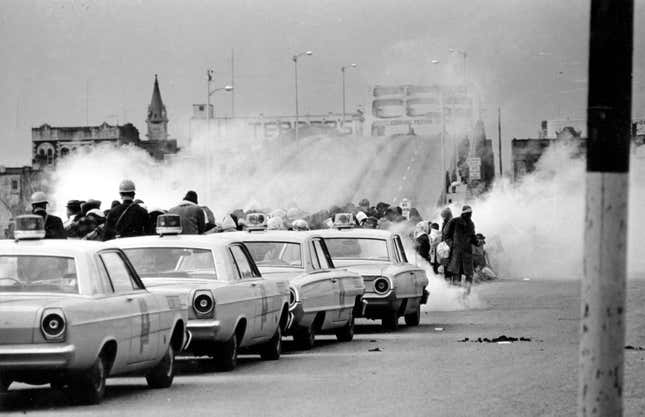 In this March 7, 1965, file photo tear gas fills the air as state troopers, ordered by Alabama Gov. George Wallace, break up a march at the Edmund Pettus Bridge in Selma, Ala., on what became known as Bloody Sunday.