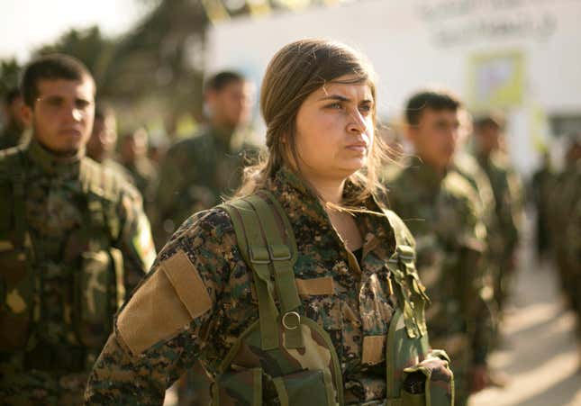 U.S.-backed Syrian Democratic Forces (SDF) stand in formation at a ceremony to mark their defeat of Islamic State militants in Baghouz, at al-Omar Oil Field base, Syria, Saturday, March 23, 2019.