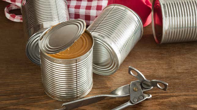 Can opener on table beside unlabeled half-open can of food