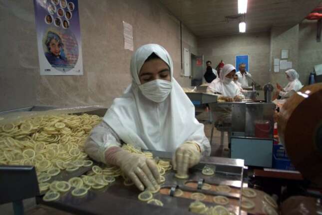 A veiled worker sorts condoms for packaging at the Takestan, Iran condom factory, Sept. 23 1999.
