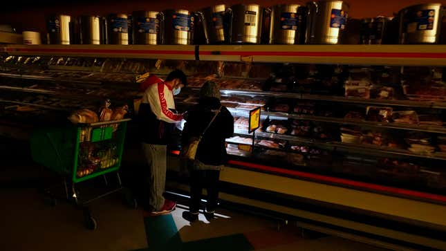 Customers use the light from a cell phone to look in the meat section of a grocery store in Dallas last week.