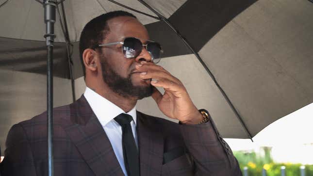 R&amp;B singer R. Kelly covers his mouth as he speaks to members of his entourage as he leaves the Leighton Criminal Courts Building following a hearing on June 26, 2019, in Chicago.