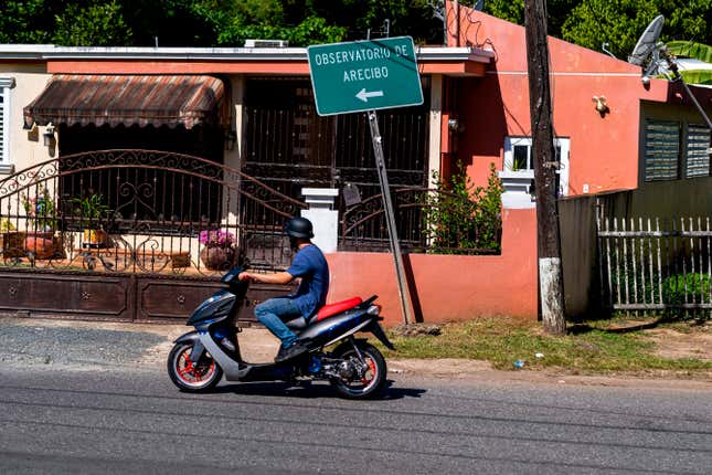 A motorcyclist drives by a road sign toward the Arecibo Observatory on December 1, 2020. 